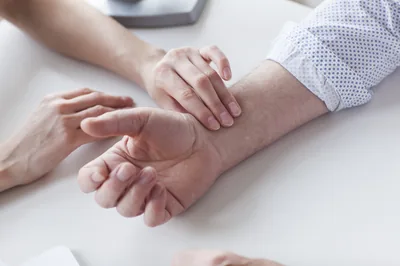 TCM pulse diagnosis: practitioner taking a patient's radial pulse at the wrist using three fingers